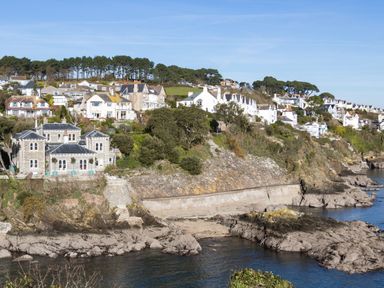 A coastal village with houses on a hill overlooking rocky shoreline and water at The Old Vicarage Retreat in Luxulyan