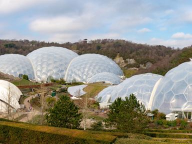 Several large hexagonal patterned domes with greenery and pathways in the foreground and hills in the background