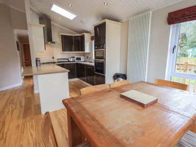 A kitchen with wooden dining table and chairs beside a window at Oakwood Lodge Langdale 3 White Cross Bay Windermere