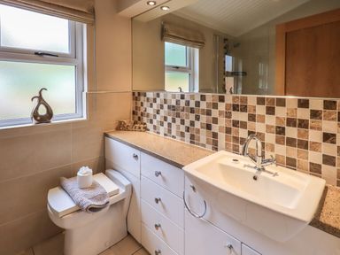 A bathroom with a toilet a sink a tiled backsplash and a countertop at Oakwood Lodge in Langdale 3 White Cross Bay Windermere