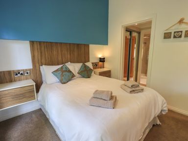 A bedroom with a double bed with folded towels and two nightstands at Oakwood Lodge in Langdale 3 White Cross Bay Windermere
