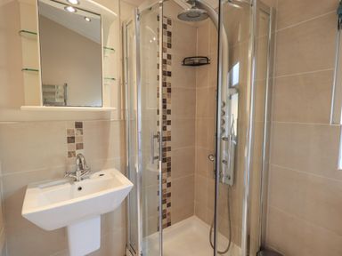 A bathroom with a corner shower enclosure and a white sink beneath a mirrored cabinet at Oakwood Lodge Langdale 3 White Cross Bay Windermere