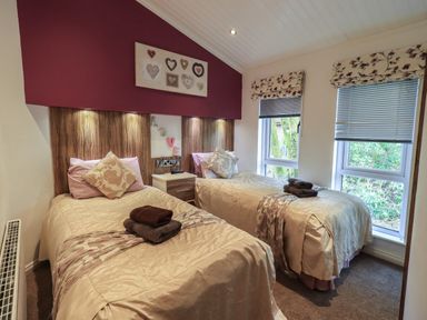 A bedroom with two single beds next to each other with a nightstand in between at Oakwood Lodge Langdale 3 White Cross Bay Windermere