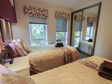 A bedroom with two single beds a nightstand with a remote control and mirrored wardrobe at Oakwood Lodge Langdale 3 White Cross Bay Windermere