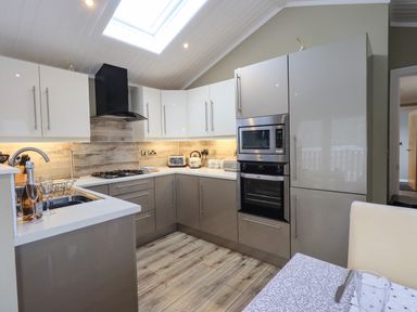 A kitchen with a built in oven microwave and refrigerator a gas stove and a sink at Lakeland View Lodge Beckside 2 Limefitt Park near Windermere