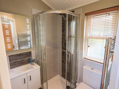 A bathroom with a corner shower enclosure a toilet a sink with cabinet and a window with blinds at Lakeland View Lodge Beckside 2 Limefitt Park near Windermere