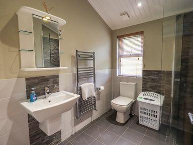 A bathroom with a sink mirror towel rack toilet window and laundry basket at Lakeland View Lodge Beckside 2 Limefitt Park near Windermere