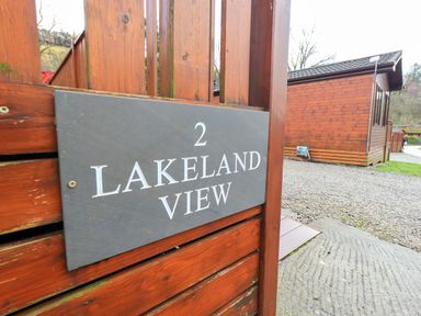 A wooden fence with a sign reading 2 Lakeland View and a wooden cabin in the background at Lakeland View Lodge Beckside 2 Limefitt Park near Windermere