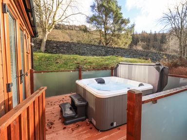 An outdoor deck area with a hot tub and steps near a wooden building at Lakeland View Lodge Beckside 2 Limefitt Park near Windermere