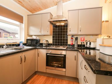 A kitchen with cabinets oven stovetop microwave toaster and kettle at Damson Lodge Thirlmere 8 White Cross Bay Windermere