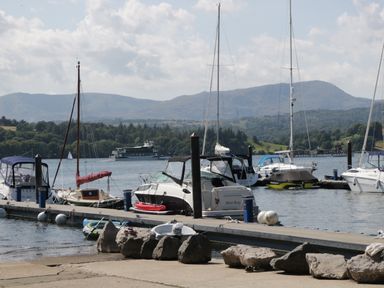 A marina with boats docked at the pier and mountains in the background at Damson Lodge in Thirlmere 8 White Cross Bay Windermere
