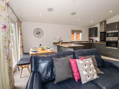 An open plan kitchen and dining area with a blue sofa and cushions at Ridgway Lodge Calgarth 40 White Cross Bay near Windermere
