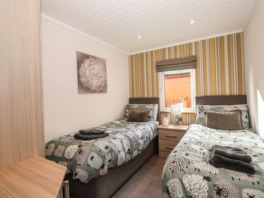 A bedroom with two single beds and a window between them at Ridgway Lodge Calgarth 40 White Cross Bay near Windermere