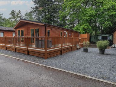 A wooden lodge with decking and gravel area at Ridgway Lodge Calgarth 40 White Cross Bay near Windermere