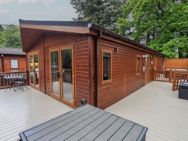 A log cabin with a deck and wooden railing at Ridgway Lodge Calgarth 40, White Cross Bay near Windermere