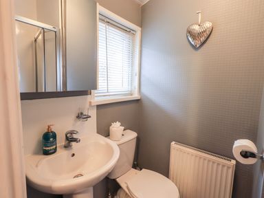 A bathroom with a sink a toilet a window a radiator and a heart-shaped decoration on the wall at Buttermere Lodge Glade 5 Fallbarrow Park near Bowness on Windermere