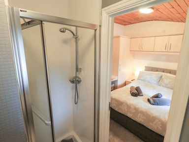 A bathroom with a shower and an adjacent bedroom with a bed and overhead cabinets at Buttermere Lodge Glade 5 Fallbarrow Park near Bowness on Windermere