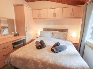 A bedroom with a double bed and rolled towels on the bed at Buttermere Lodge in Glade 5 Fallbarrow Park near Bowness on Windermere