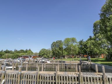 A wooden dock area with boats moored and green trees in the background at Rydal Lodge Grasmere 24 White Cross Bay near Windermere