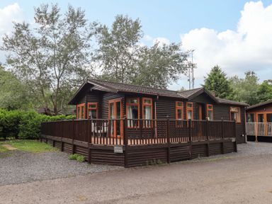 A lodge with a deck surrounded by trees at Rydal Lodge in Grasmere 24, White Cross Bay near Windermere