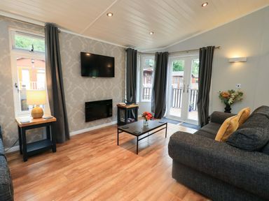 A living room with a sofa and television at Rydal Lodge Grasmere 24, White Cross Bay near Windermere