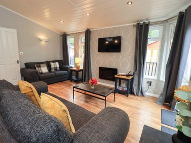 A living room with a television and sofas at Rydal Lodge Grasmere 24, White Cross Bay near Windermere