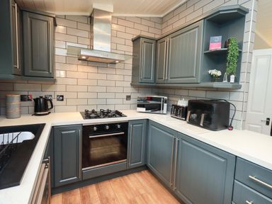 A kitchen with cabinets, sink, gas stove, microwave, and kettle at Rydal Lodge Grasmere 24, White Cross Bay near Windermere