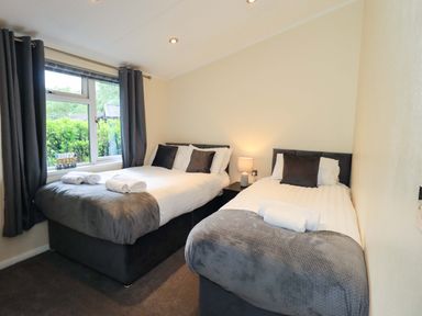 A bedroom with two beds and a window at Rydal Lodge Grasmere 24, White Cross Bay near Windermere