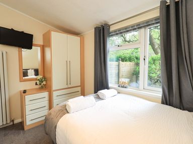 A bedroom with a bed and wardrobe at Rydal Lodge, Grasmere 24, White Cross Bay near Windermere