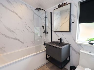 A bathroom featuring a bathtub, shower, mirror, sink, and toilet at Rydal Lodge Grasmere 24, White Cross Bay near Windermere