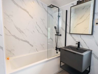 A bathroom with a bathtub, shower, and sink at Rydal Lodge in Grasmere 24, White Cross Bay near Windermere