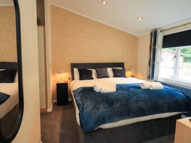 A bedroom with a bed, bedside lamp, and window at Rydal Lodge in Grasmere 24, White Cross Bay near Windermere