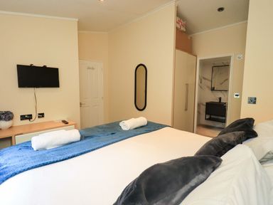 A bedroom with a bed, television, and bathroom access at Rydal Lodge in Grasmere 24, White Cross Bay near Windermere