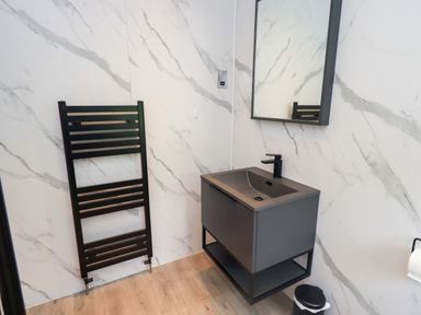 A bathroom featuring a vanity, mirror, towel rail, and waste bin at Rydal Lodge Grasmere 24, White Cross Bay near Windermere