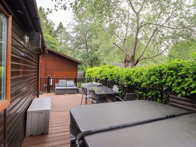 An outdoor deck area with seating and a hot tub at Rydal Lodge Grasmere 24, White Cross Bay near Windermere