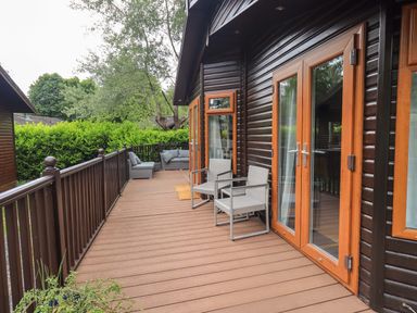 A deck area with outdoor chairs and a sofa at Rydal Lodge Grasmere 24, White Cross Bay near Windermere