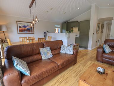 A living room with brown leather sofas and a wooden dining table with chairs at Wansfell Retreat Lodge Wansfell 4 Limefitt Park near Windermere