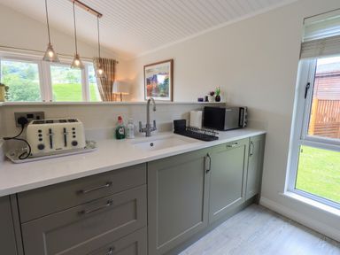 A kitchen counter with a toaster dish soap sink microwave and window at Wansfell Retreat Lodge Wansfell 4 Limefitt Park near Windermere