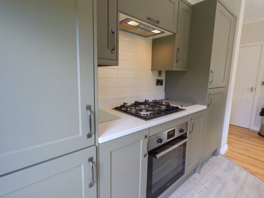 A kitchen with gray cabinets a gas stove and oven at Wansfell Retreat Lodge Wansfell 4 Limefitt Park near Windermere