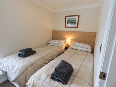 A bedroom with two single beds with towels on them and a lamp between the beds at Wansfell Retreat Lodge Wansfell 4 Limefitt Park near Windermere