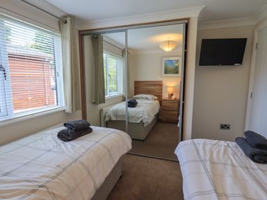 A bedroom with two single beds a wall-mounted television and mirrored sliding wardrobe doors at Wansfell Retreat Lodge Wansfell 4 Limefitt Park near Windermere