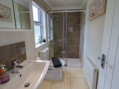 A bathroom with a sink, toilet with towel, window, shower enclosure, radiator, and wall art at Wansfell Retreat Lodge Wansfell 4 Limefitt Park near Windermere
