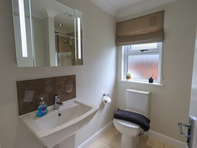 A bathroom with a sink, toilet, window with a blind, and mirror cabinet at Wansfell Retreat Lodge Wansfell 4 Limefitt Park near Windermere