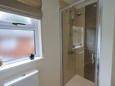 A bathroom with a tiled shower enclosure a frosted window and a toilet at Wansfell Retreat Lodge Wansfell 4 Limefitt Park near Windermere