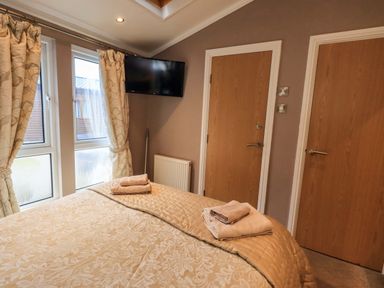 A bedroom with a bed and television at Elder Lodge Kirkstone 5 Limefitt Park near Windermere