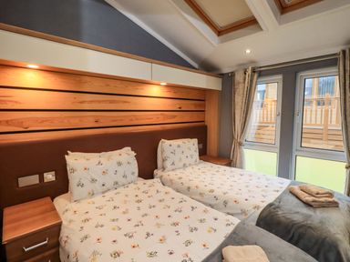 A bedroom with two beds and windows at Elder Lodge, Kirkstone 5, Limefitt Park near Windermere