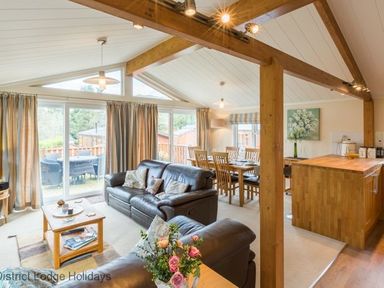 A living area with leather sofas a wooden coffee table and dining table near a kitchen island at Sheffield Pike Lodge Ullswater 8 Limefitt Park near Windermere