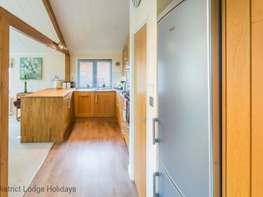 A kitchen with wooden cabinets a silver refrigerator and a wooden kitchen island at Sheffield Pike Lodge in Ullswater 8 Limefitt Park near Windermere