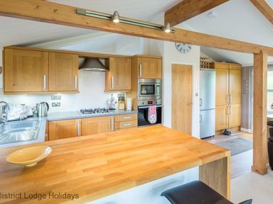 A kitchen with wooden cabinets a gas stove a refrigerator and a wooden countertop at Sheffield Pike Lodge Ullswater 8 Limefitt Park near Windermere
