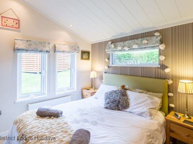 A bedroom with a bed pillows bedside tables lamps and windows at Sheffield Pike Lodge in Ullswater 8 Limefitt Park near Windermere